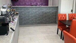 Una cocina moderna con una isla integrada, una zona de estar con sillas anaranjadas y una pared de acento morada.