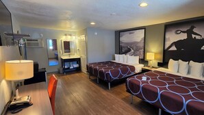 Habitación de hotel con dos camas, un escritorio con lámpara, un espejo y un televisor montado.