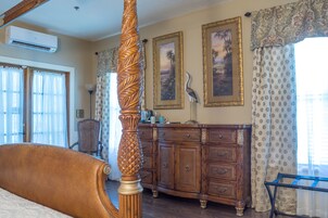 A bedroom with a four-poster bed, a wooden dresser, and a desk with a lamp.