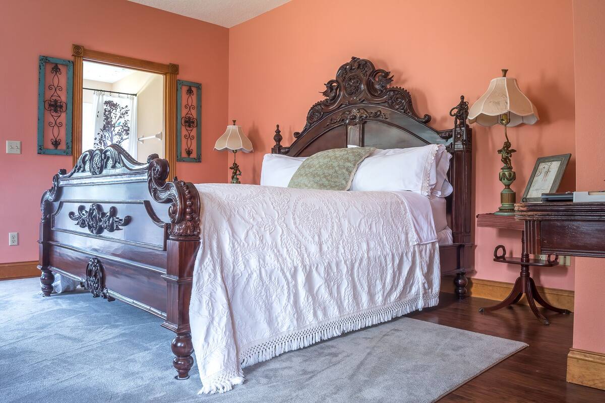 A bedroom with a large bed, ornate dresser, and a mirror.
