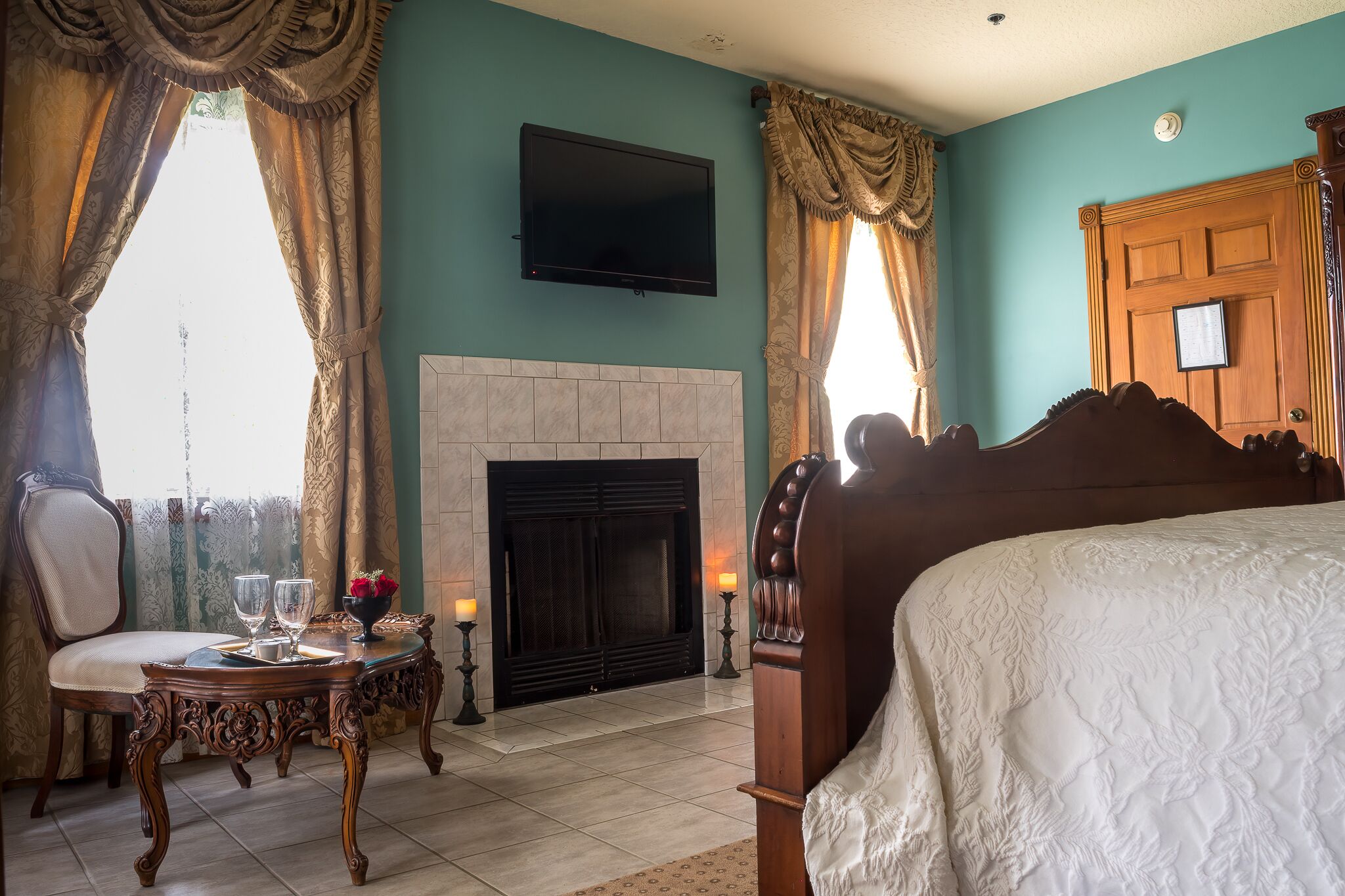 A bedroom with a large bed, a fireplace, a television, and a dining area with a table and chairs.