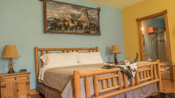 A wooden bed with a headboard, a nightstand with a lamp, and a painting of horses on the wall.