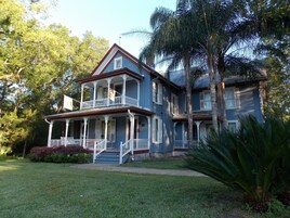 A two-story house with a porch, surrounded by trees and a well-maintained lawn.