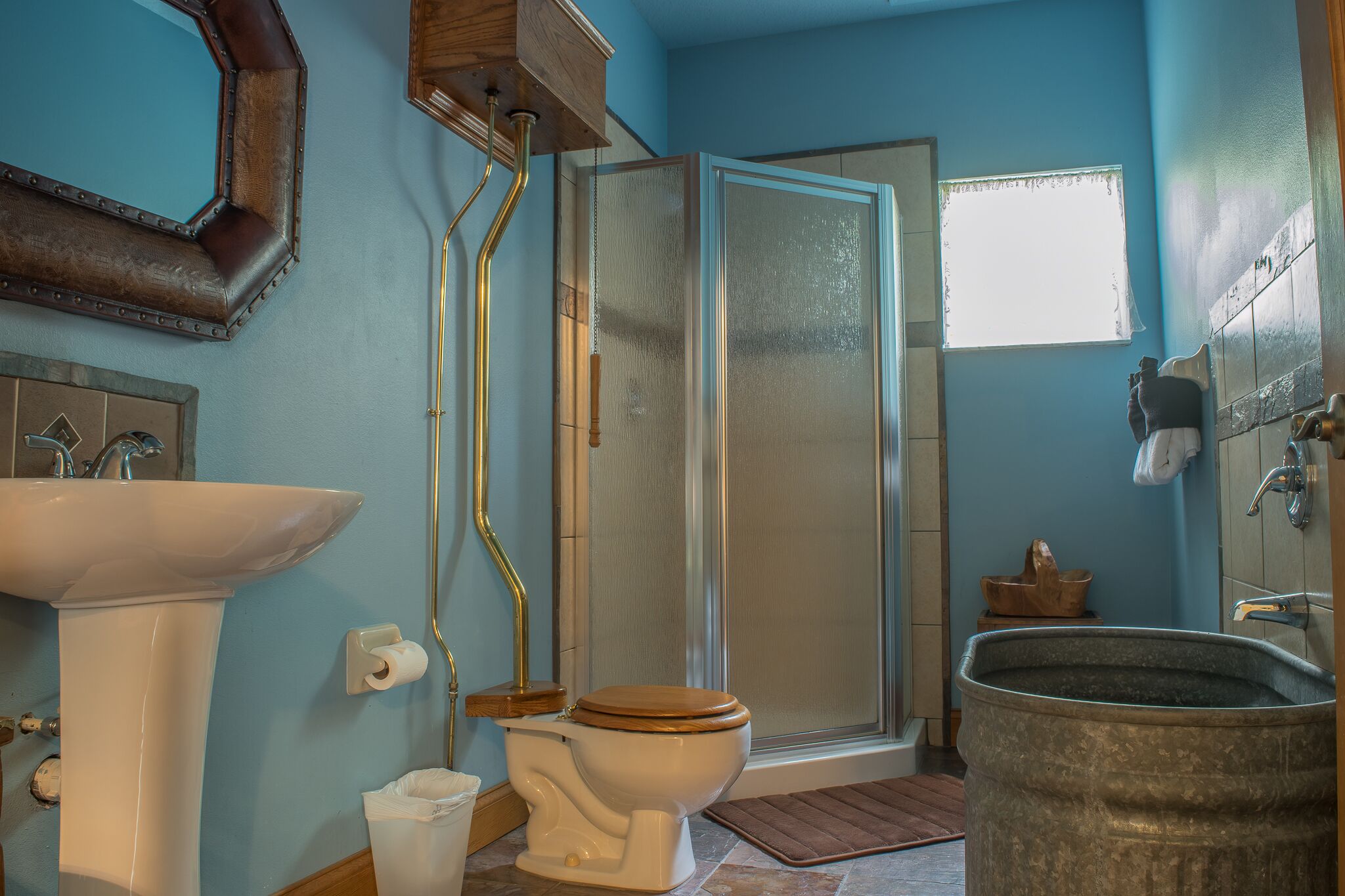 Un baño con lavamanos blanco, inodoro, cabina de ducha y un lavabo metálico grande.