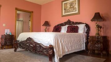 A bedroom with a large bed, two nightstands, a mirror, and a painting on the wall.