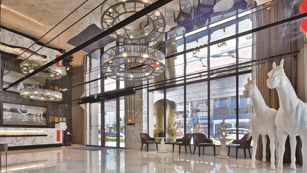 A modern lobby with a marble reception desk, multiple seating areas, and large windows offering a view of the street. - Wo (Kaohsiung)