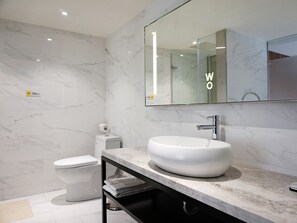 A modern bathroom with a white sink, a toilet, and a large mirror.