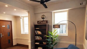 A modern lobby with a wooden floor, a bookshelf labeled "3RD FLOOR", a potted plant, and a ceiling fan. - CityRest Fort - Hostel (Colombo)