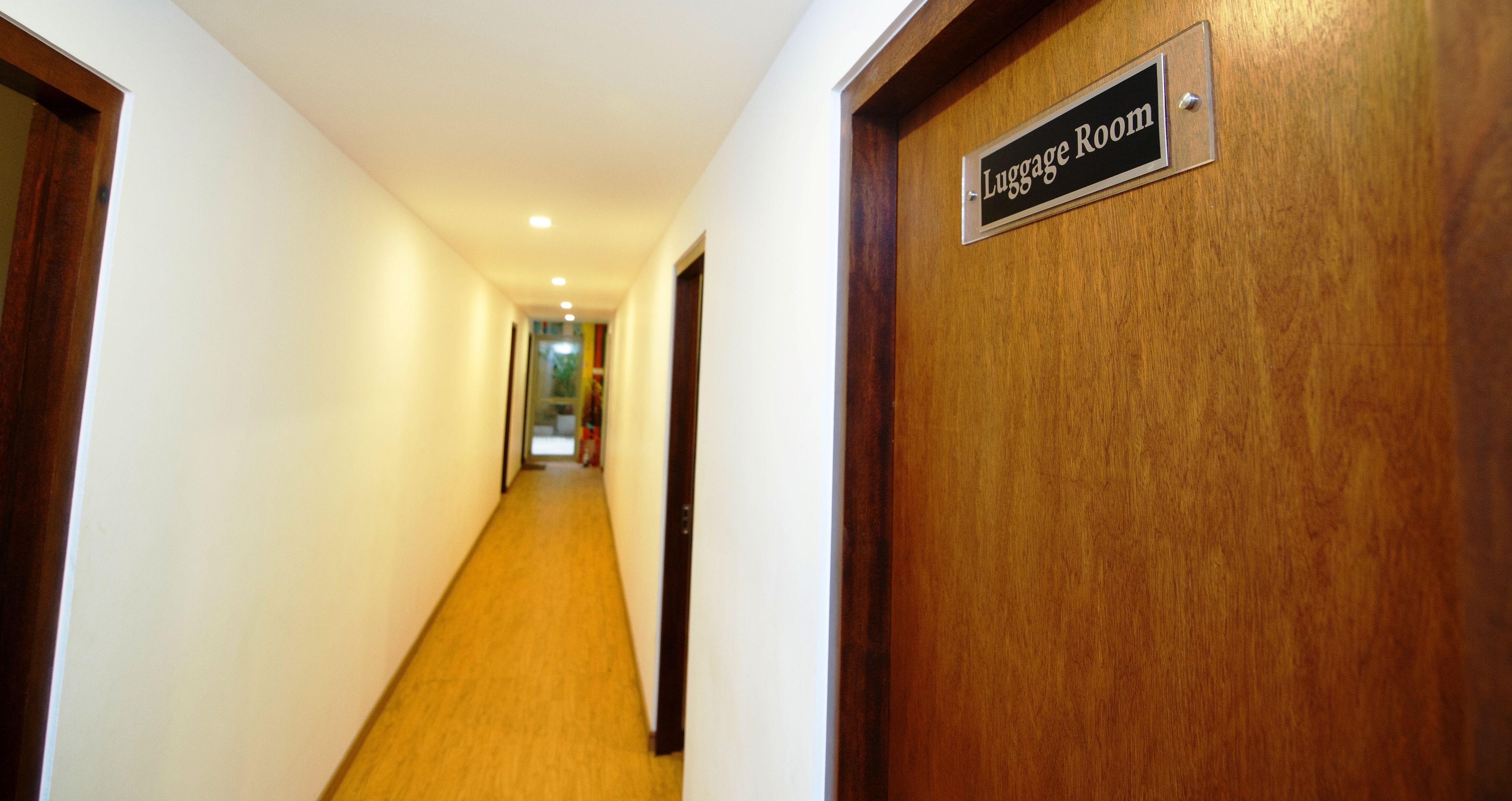Un couloir menant à une salle de stockage des bagages, avec une porte en bois et une pancarte.