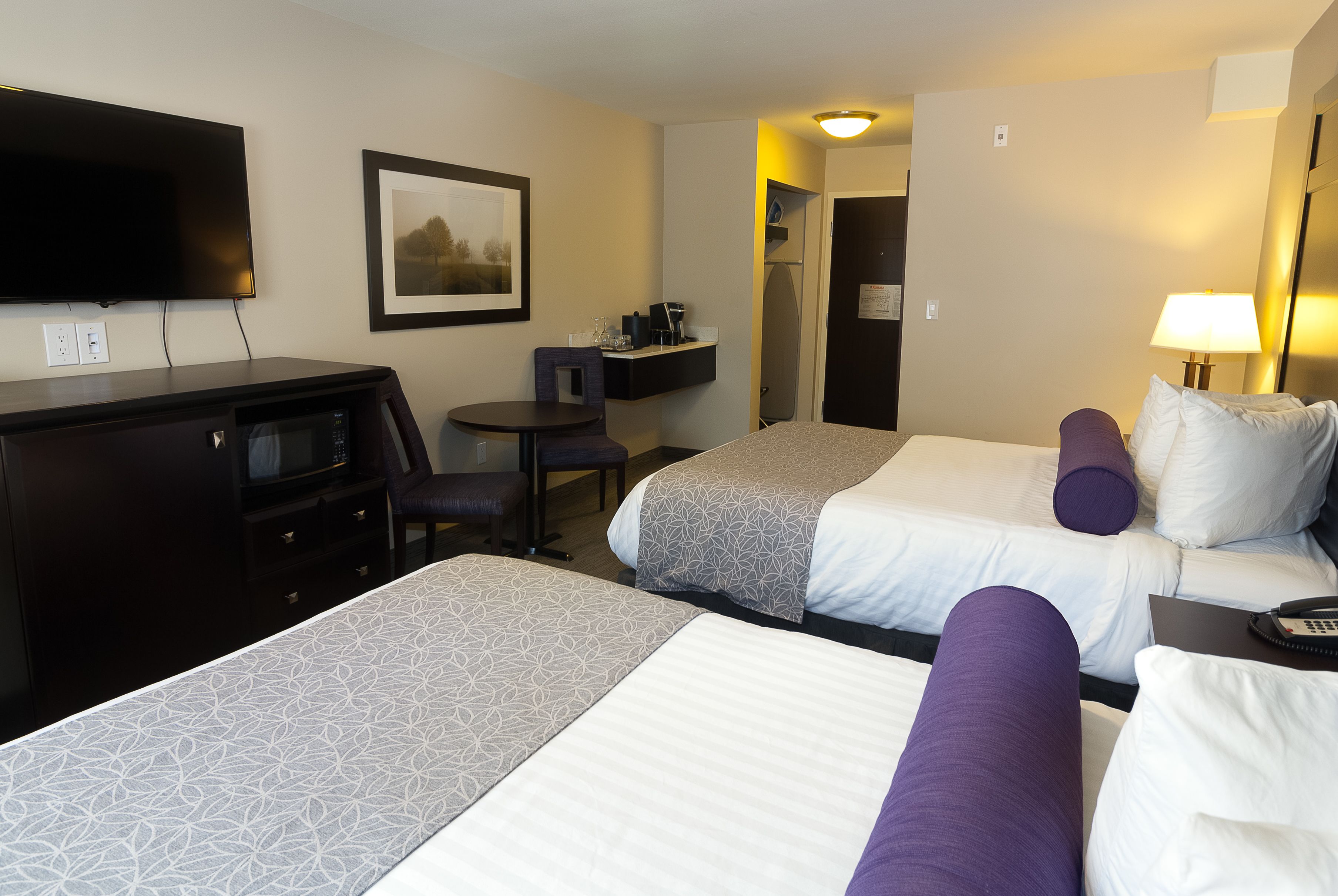 Habitación de hotel con dos camas, un escritorio, un televisor y una pequeña zona de estar.