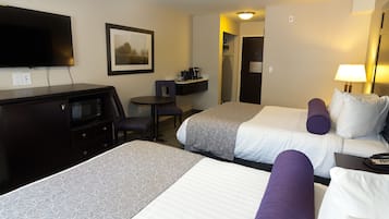 Habitación de hotel con dos camas, un escritorio, un televisor y una pequeña zona de estar.