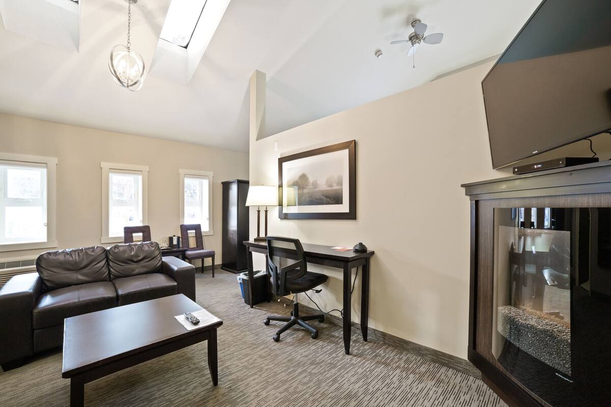 A modern living room with a sofa, a desk, and a television.