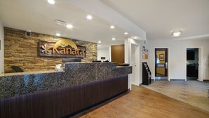 Un área de recepción con una pared de piedra, un mostrador de madera y un letrero que dice "The Kanata".