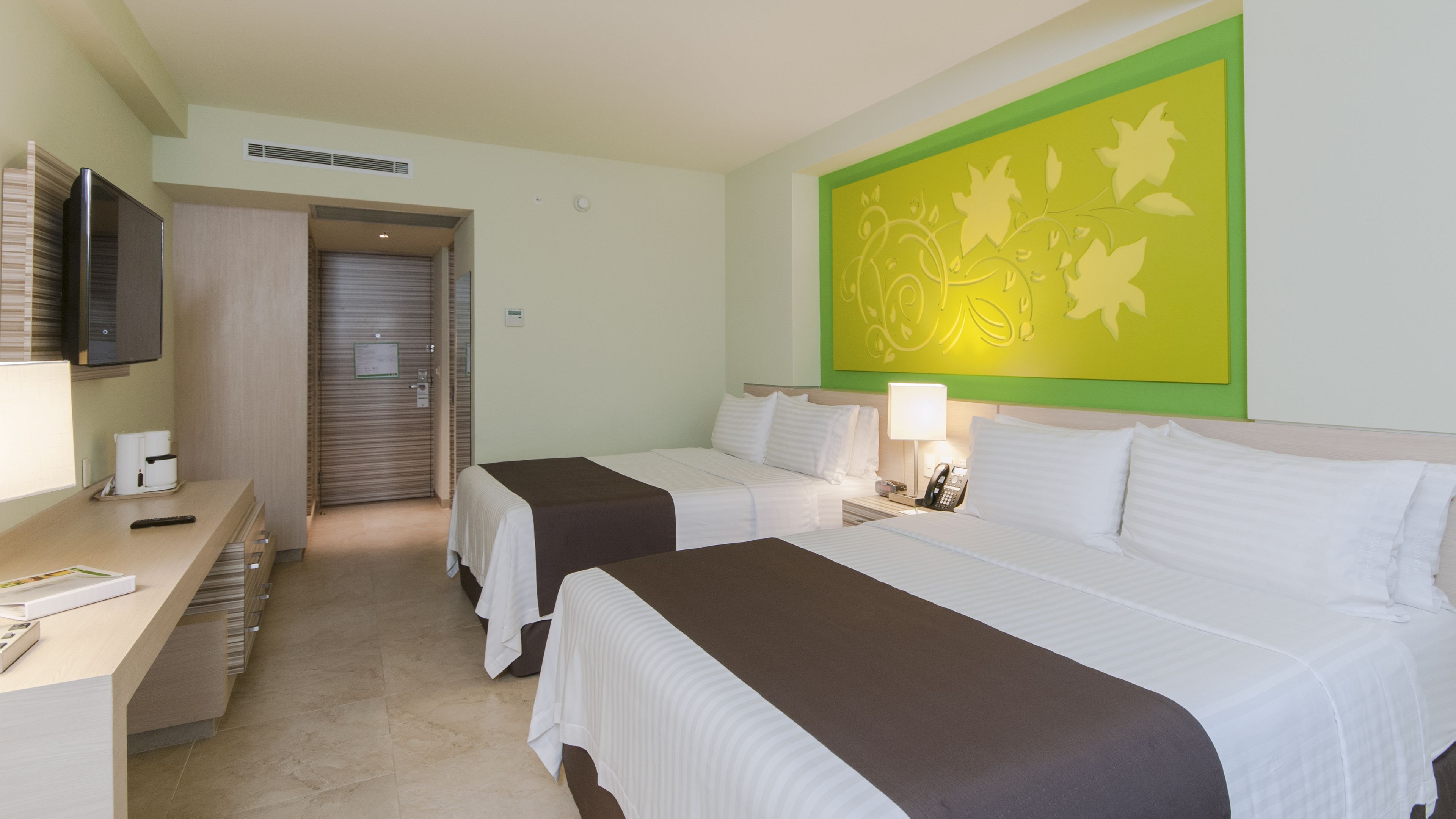 Une chambre d’hôtel avec deux lits, un bureau avec un téléphone et une télévision.