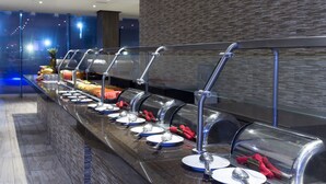 A buffet setup with multiple self-service stations, each with a glass cover and utensils. - Holiday Inn Coatzacoalcos by IHG (Coatzacoalcos)
