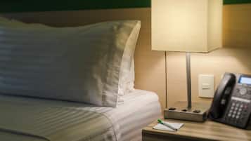 A hotel room with a bed, a bedside lamp, a telephone, and a notepad on the nightstand.