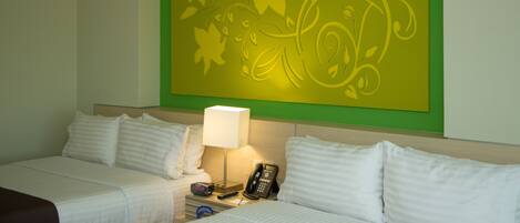Habitación de hotel con dos camas, una mesita de noche con lámpara, teléfono y un adorno en la pared.