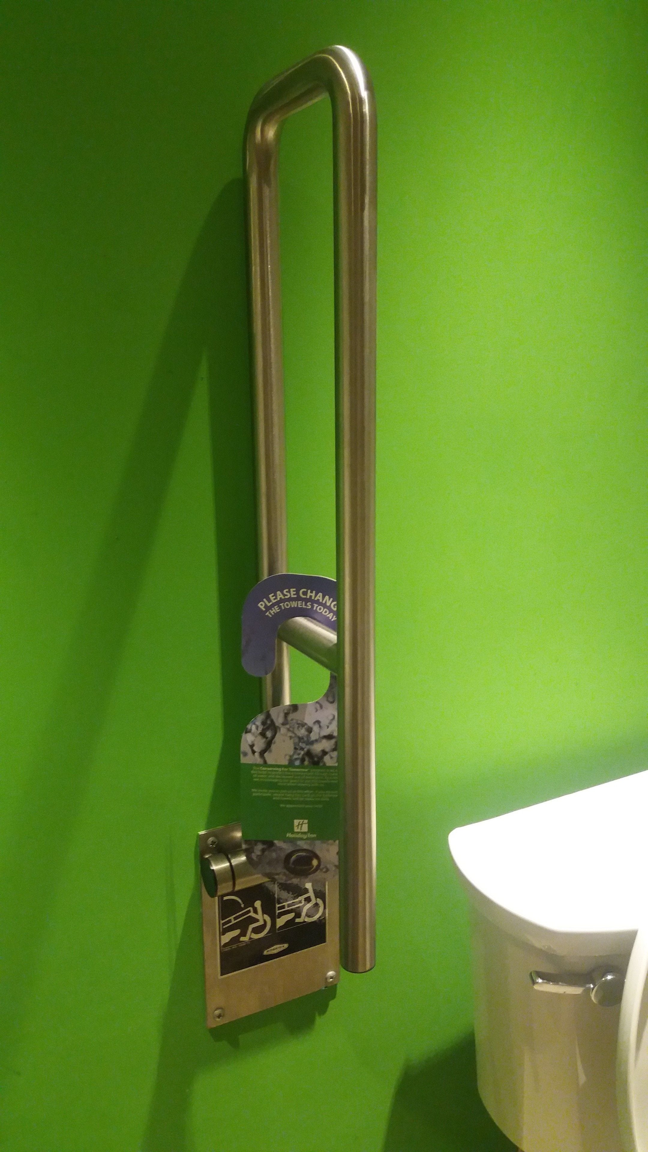 Un secador de manos instalado en una pared verde junto a un inodoro blanco.