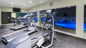 Un gimnasio con cintas de correr, elípticas y una máquina de remo.