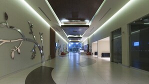Un pasillo moderno con un diseño de piso curvo, iluminación empotrada y una pantalla digital en la pared derecha.