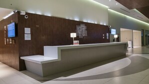 A modern reception desk with a flat surface, a small counter, and a wall-mounted TV. - Holiday Inn Coatzacoalcos by IHG (Coatzacoalcos)