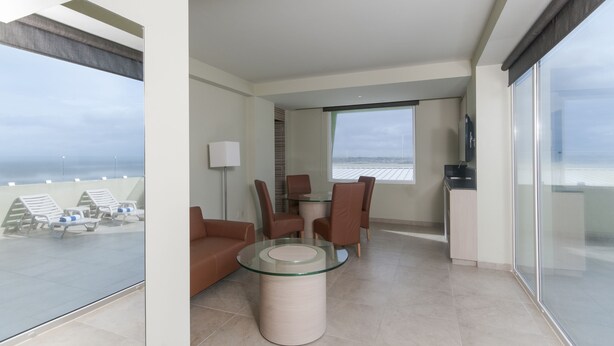 Una sala de estar moderna con una mesa de vidrio, sillas de cuero, un sofá y un televisor.