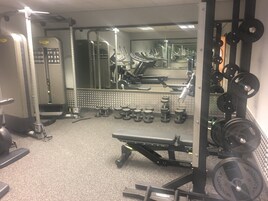 Uma academia com diversos equipamentos de exercício, incluindo esteiras, aparelhos de musculação e pesos livres.