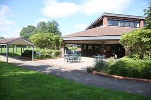 A building with a covered patio area, outdoor seating, and a small garden. - Yarnfield Park Training Centre (Stone)
