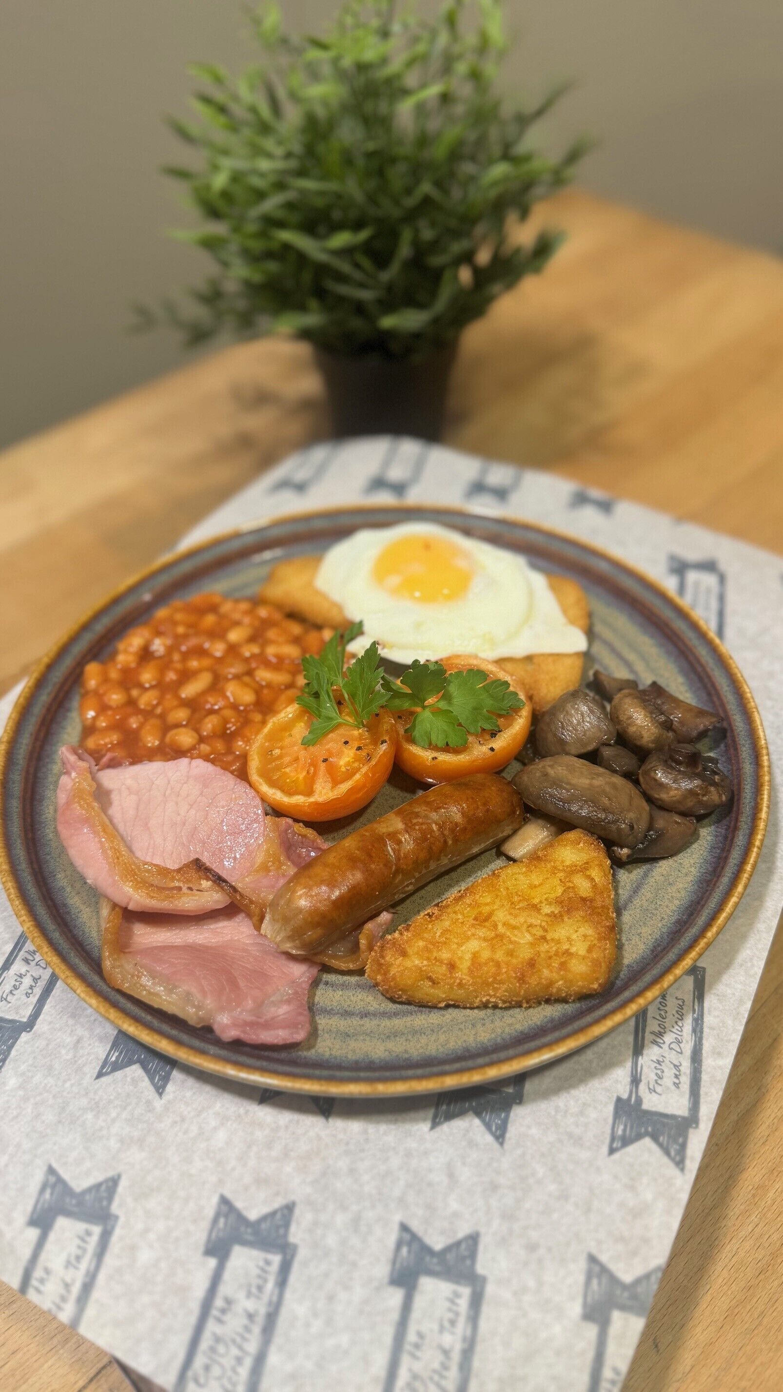 Une assiette de nourriture pour le petit-déjeuner comprenant des œufs, des haricots, des tomates, des champignons, des saucisses et du jambon.