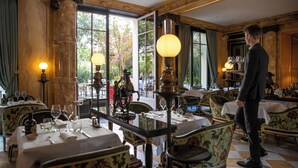 A dining area with tables set for service, ornate chairs, and a waiter. - La Reserve Paris Hotel and Spa (Paris)