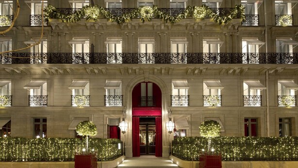 A grand hotel facade with ornate balconies, a central entrance with red doors, and decorative lighting. - La Reserve Paris Hotel and Spa (Paris)