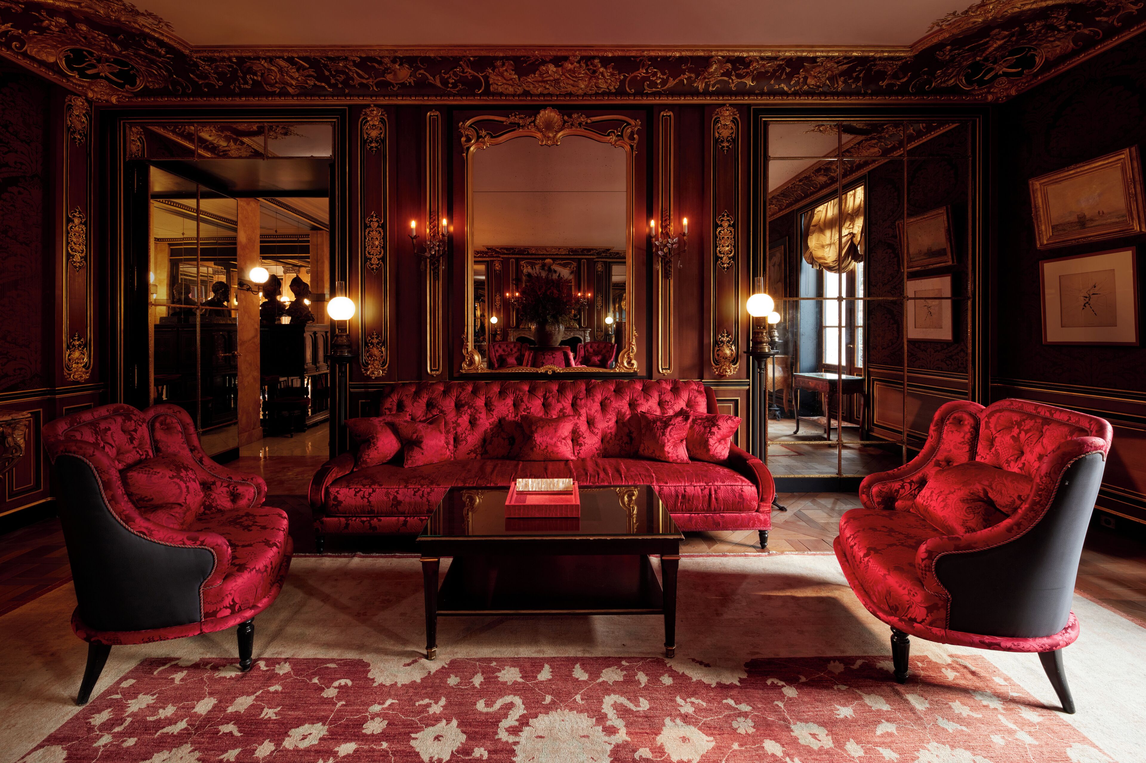 A luxurious room with a red sofa, two armchairs, and a coffee table.