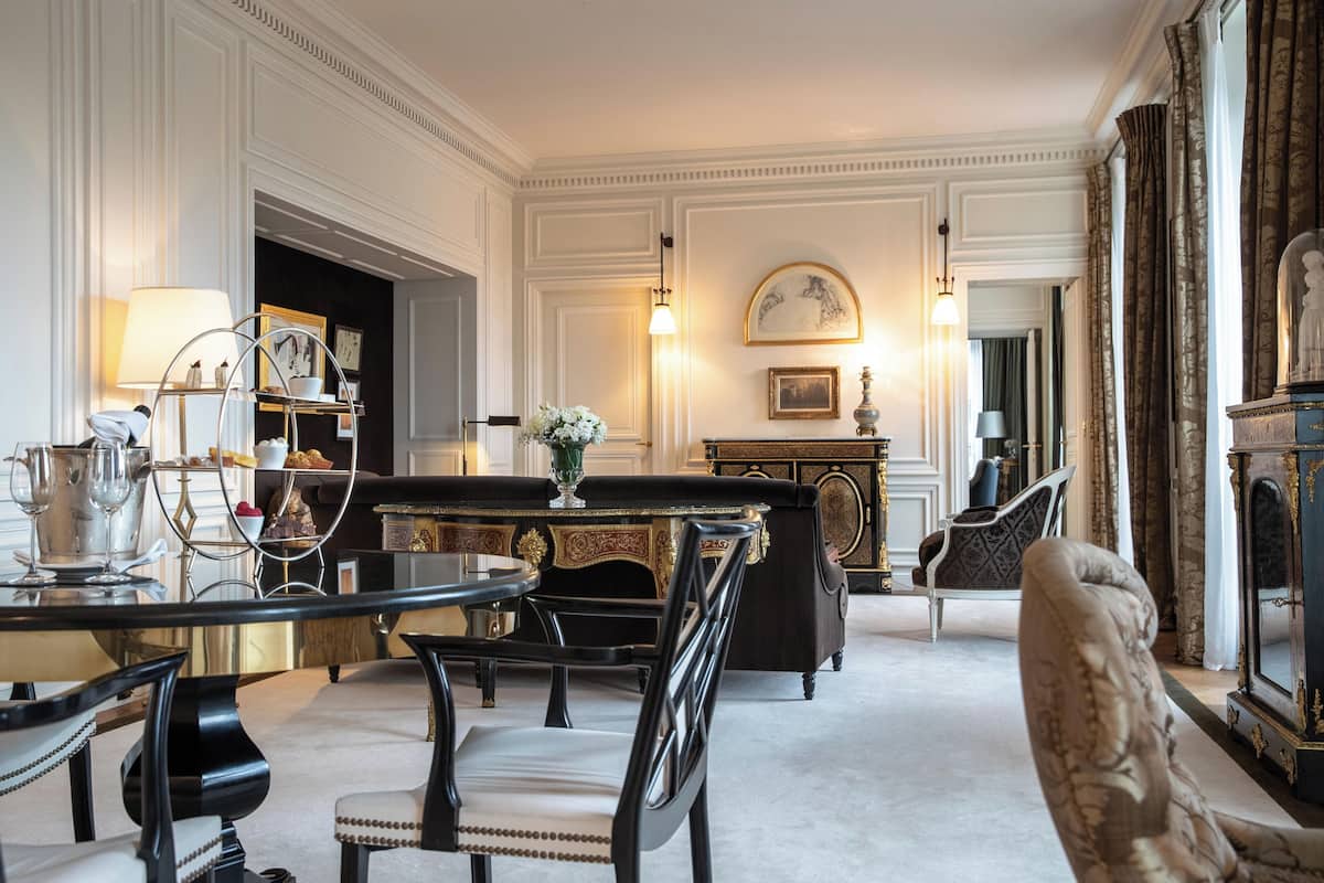 A formal dining room with a table set for four, surrounded by ornate chairs.