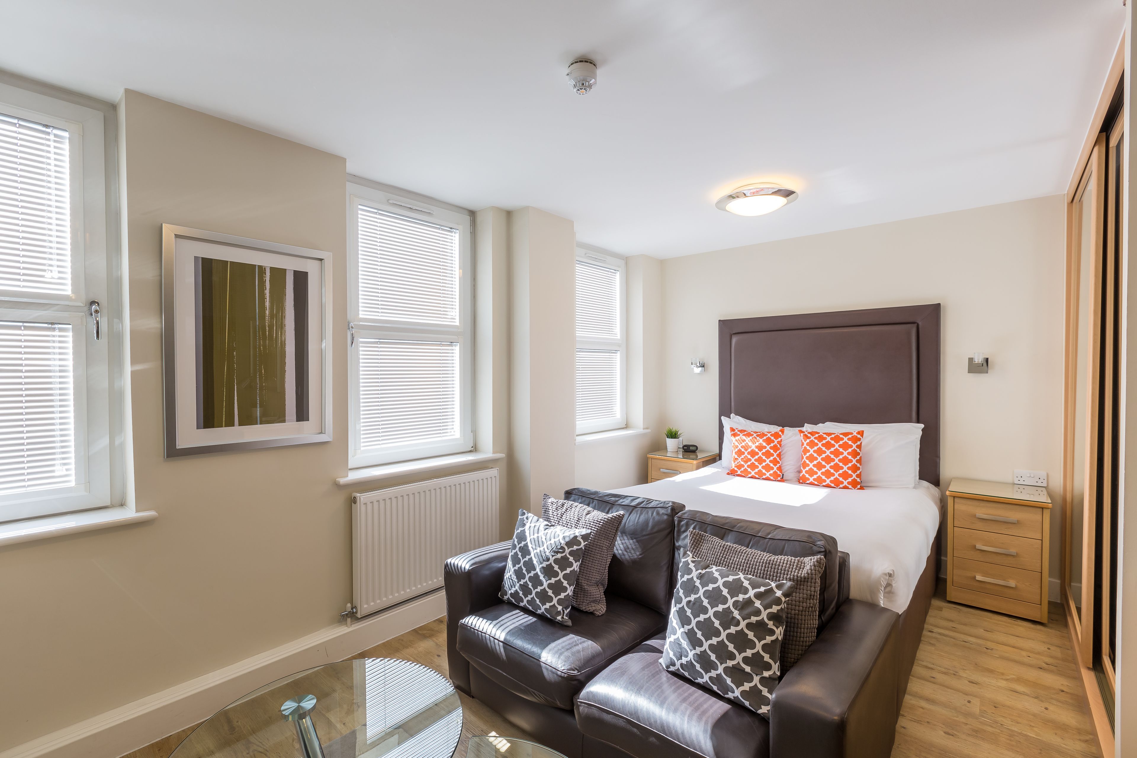 A modern bedroom with a large bed, a leather sofa, and a glass coffee table.
