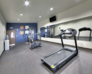 A gym with treadmills, elliptical machines, and a water dispenser.