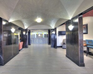 A hotel lobby with a reception desk, seating area, and a television.