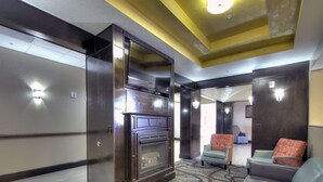 A lobby with a fireplace, seating area, and a patterned carpet. - Comfort Inn & Suites Fort Worth West I-30 NAS JRB (Fort Worth)