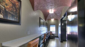A hallway with a long counter, chairs, a painting, and a ceiling light. - Comfort Inn & Suites Fort Worth West I-30 NAS JRB (Fort Worth)