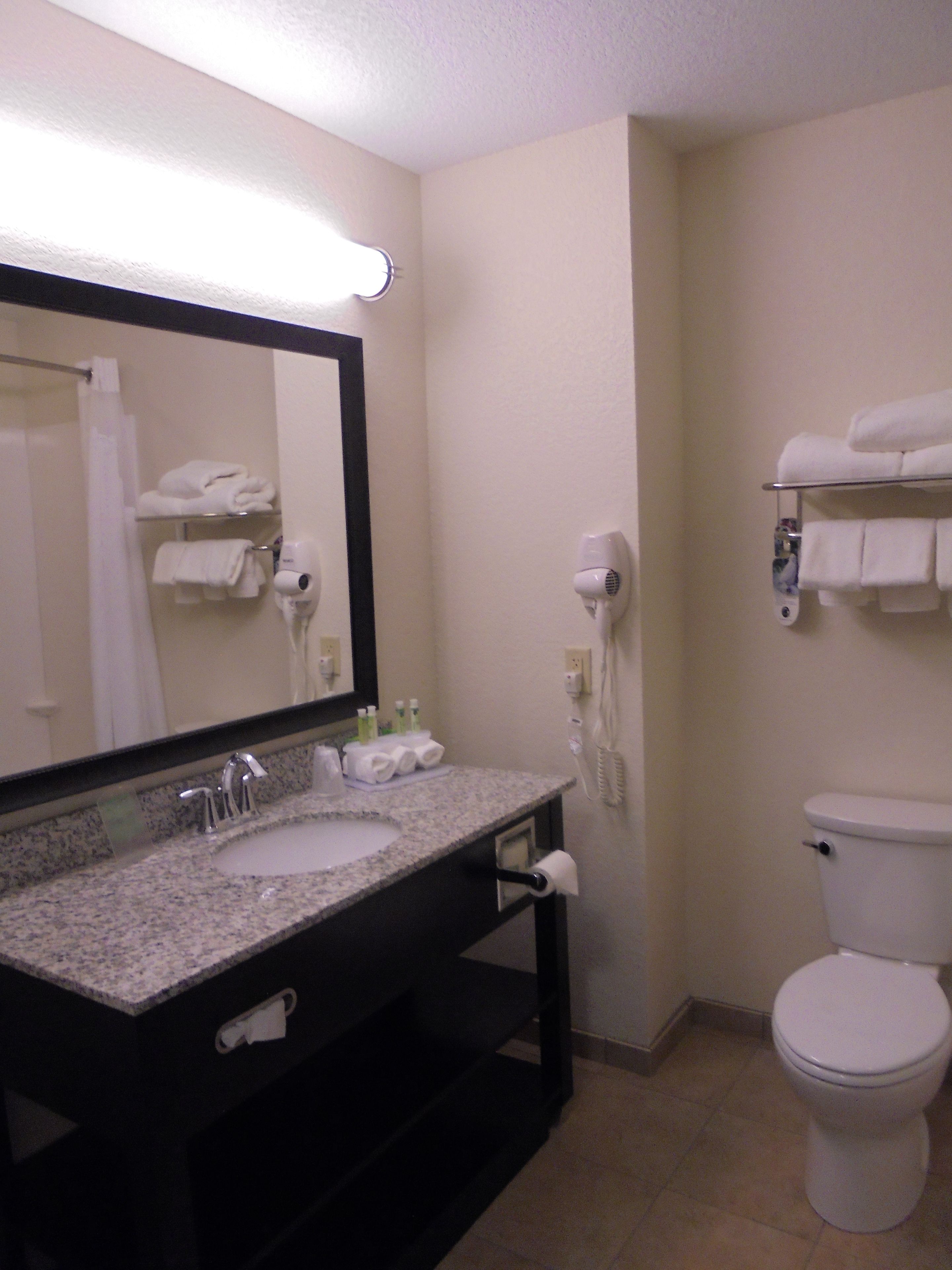 A bathroom with a sink, mirror, towel rack, and toilet.