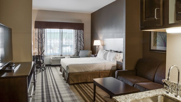 Une chambre d’hôtel équipée d’un lit, d’un bureau, d’un canapé, d’une télévision et d’une salle de bain avec un lavabo.