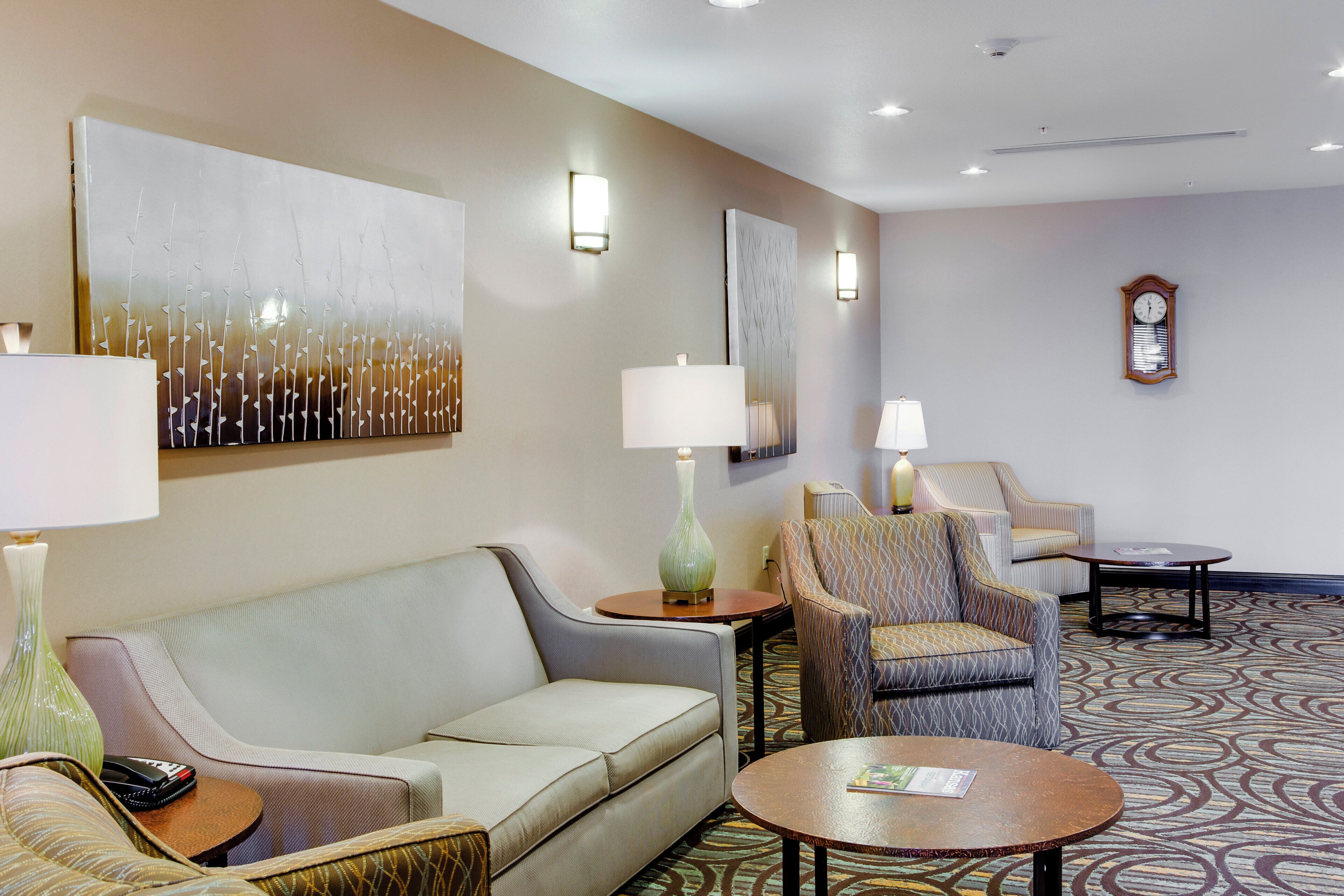 Eine Hotelhalle mit einer Couch, Sesseln, einem Couchtisch und einer Wanduhr.