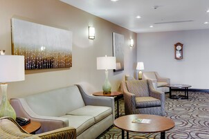 Un vestíbulo de hotel con un sofá, sillones, una mesa de centro y un reloj en la pared.