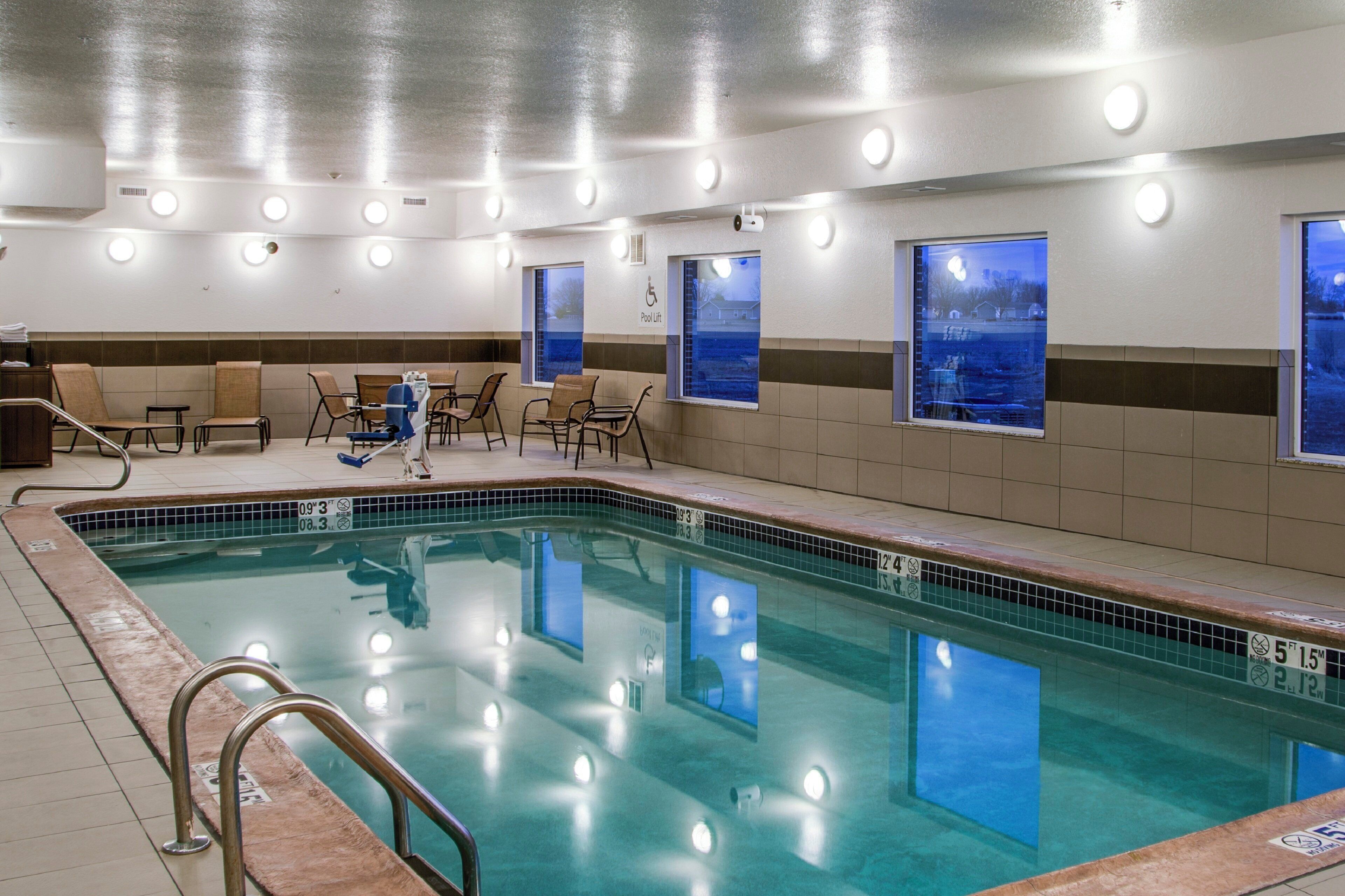 A swimming pool with a lifeguard chair, lounge chairs, and a pool lift.