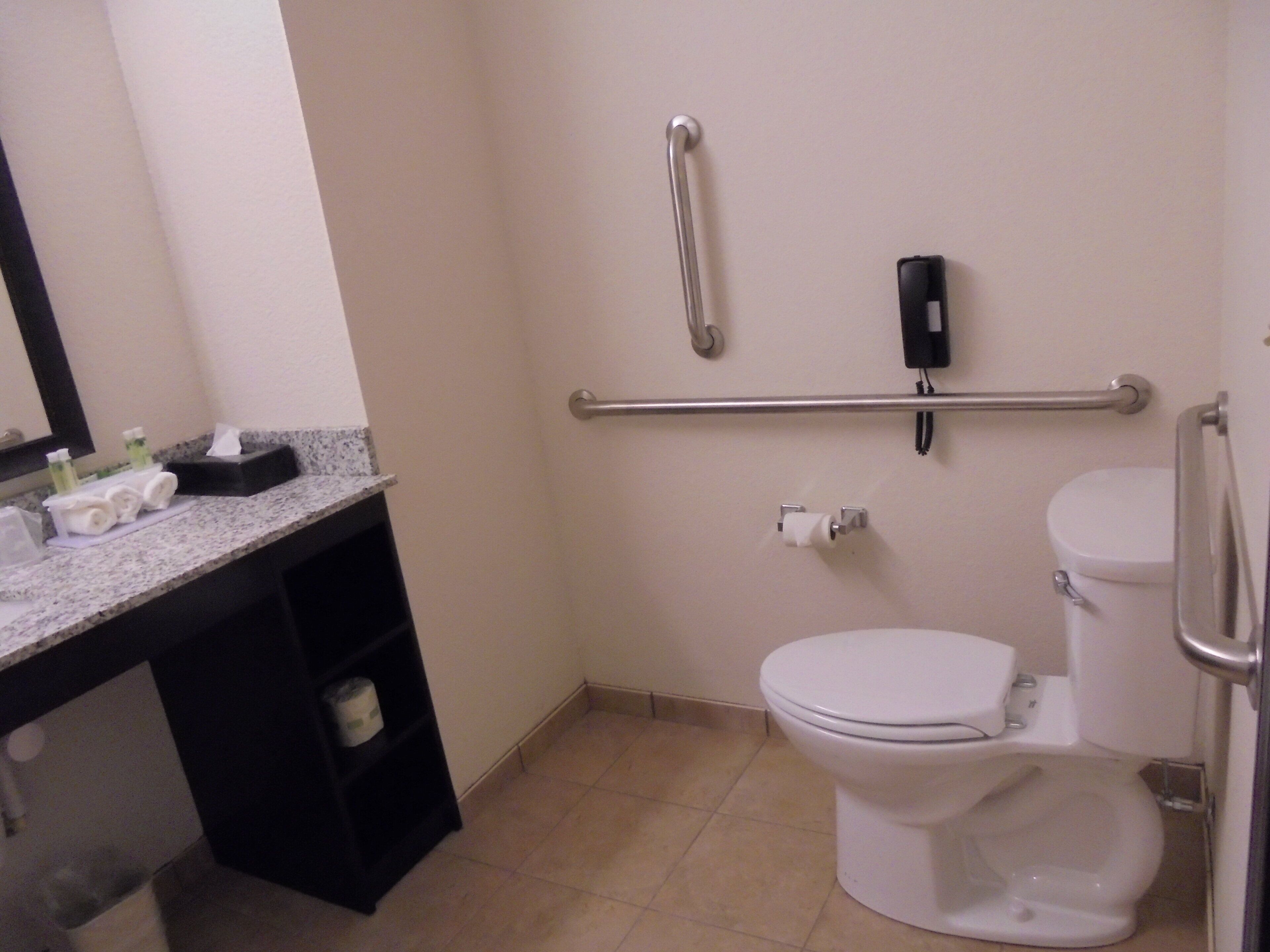 Een standaard hotelbadkamer met toilet, bidet, handdroger en een handdoekrek.