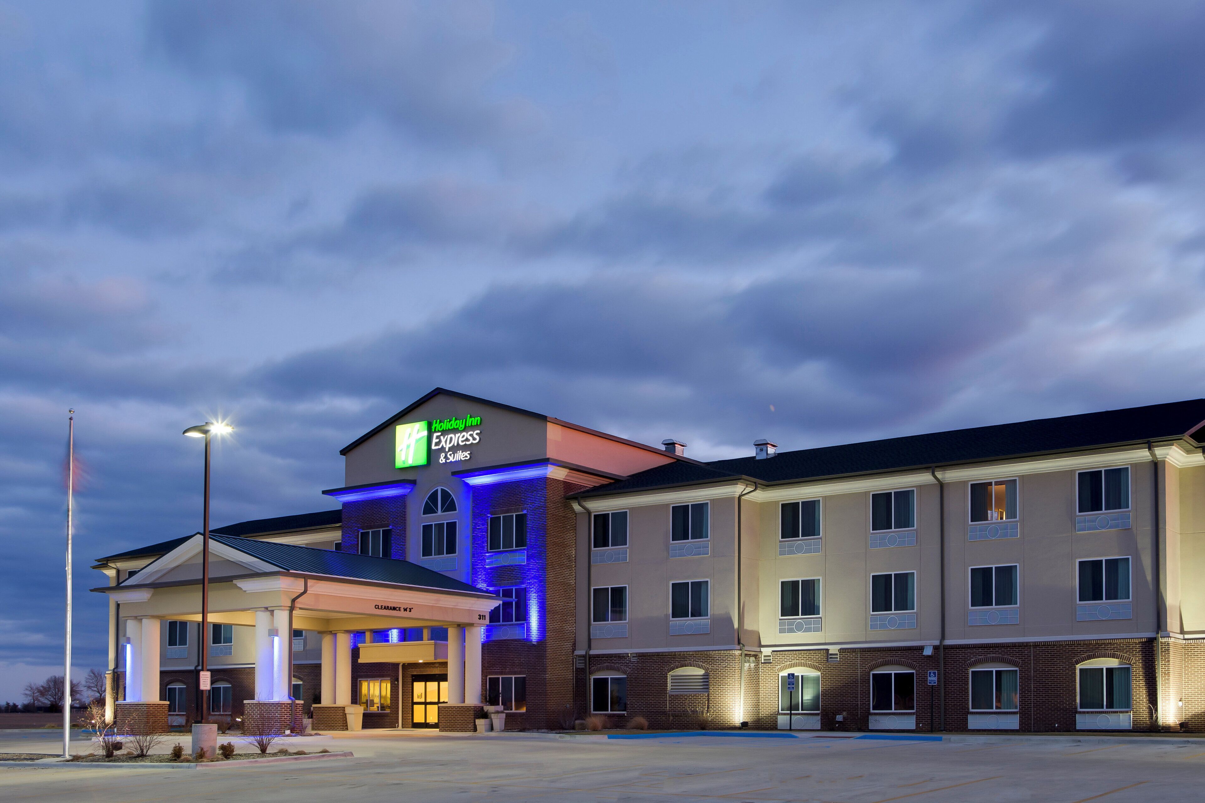 A Holiday Inn Express & Suites building with a clear sky and a parking lot in front.
