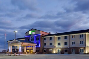 Edificio de Holiday Inn Express & Suites con cielo despejado y estacionamiento al frente.