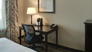Une chambre d’hôtel équipée d’un lit, d’un bureau avec une chaise, d’une lampe, d’un téléphone et d’une machine à café.