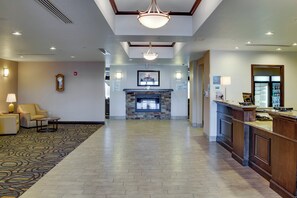 A hotel lobby with a reception desk, a fireplace, a clock, and a patterned carpet. - Holiday Inn Express & Suites Nevada by IHG (Nevada)