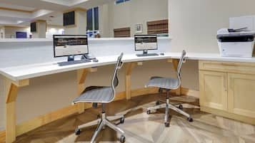 Un espacio de oficina moderno con dos escritorios, sillas e impresora.