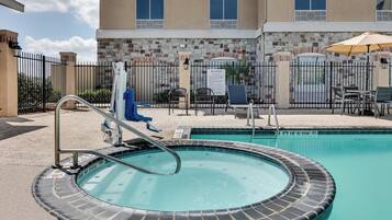 A pool area with a hot tub, lounge chairs, and a sign indicating a 15m depth limit.